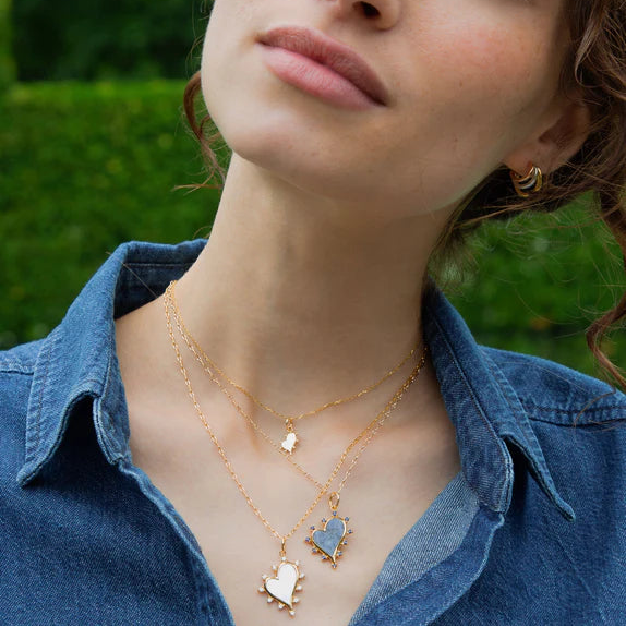 Woman wearing yellow gold white mother of pearl and diamond heart pendant necklace