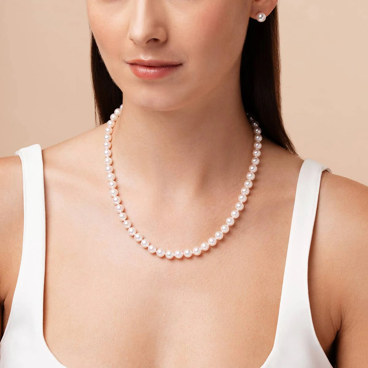 Woman wearing a pearl necklace against a beige background