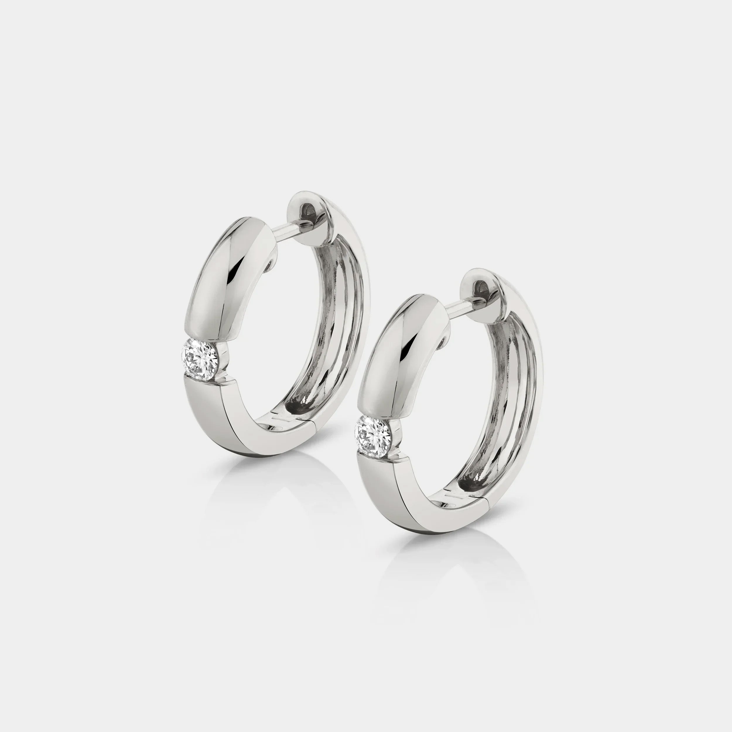 White gold huggie earrings with diamonds on grey background