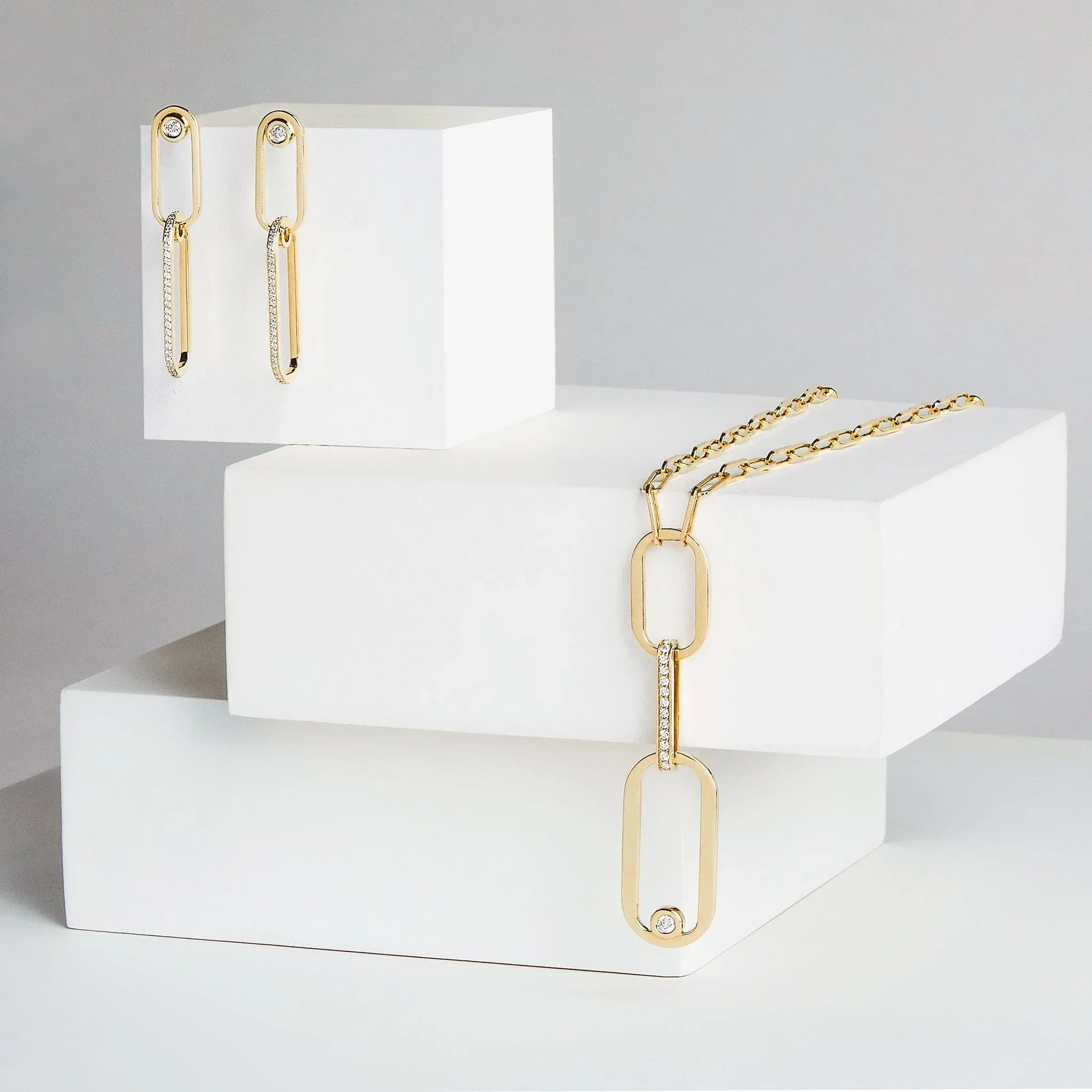 Yellow gold diamond paperclip earrings and pendant necklace set on white boxes