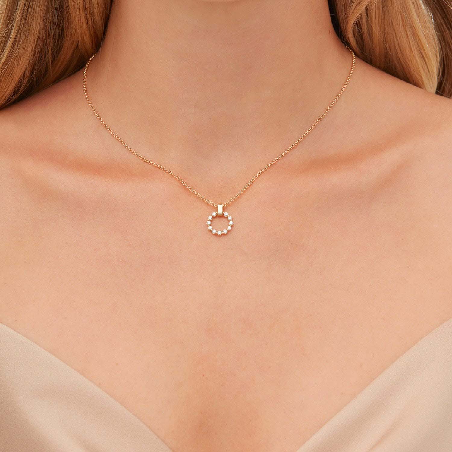 Woman wearing yellow gold circular diamond pendant necklace