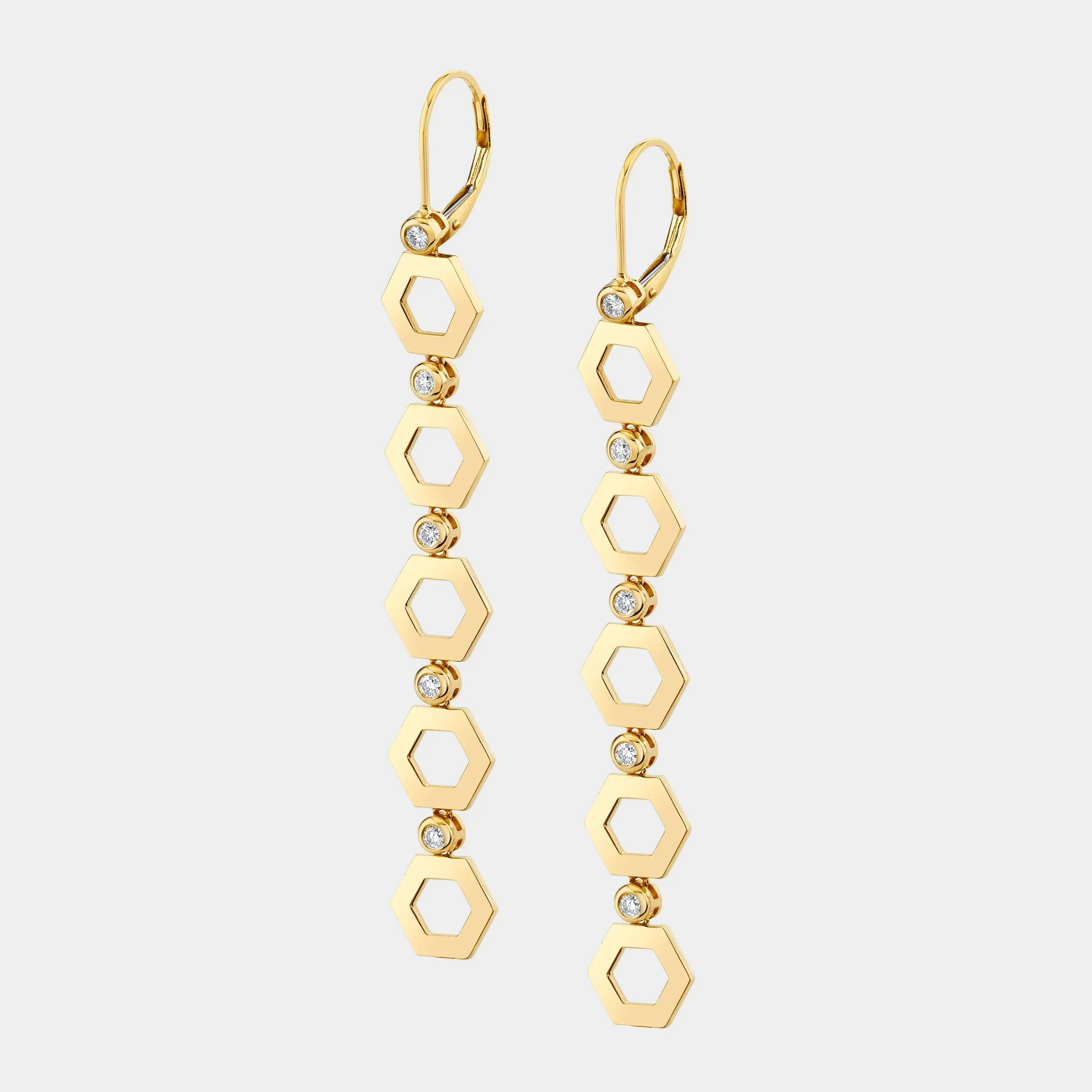 Yellow gold hex infinity drop earrings on grey background, front angle view