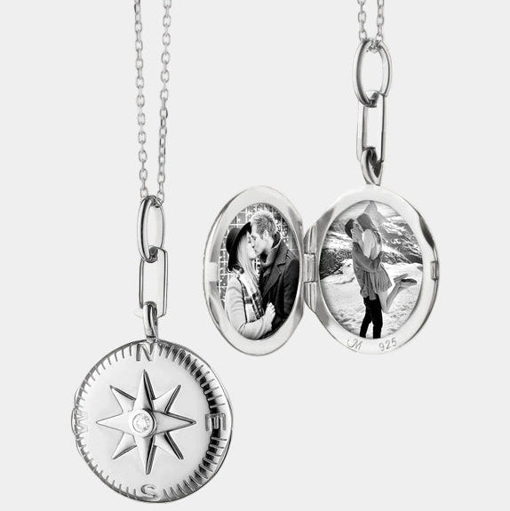 Silver pendant necklace with compass and two photos on grey background