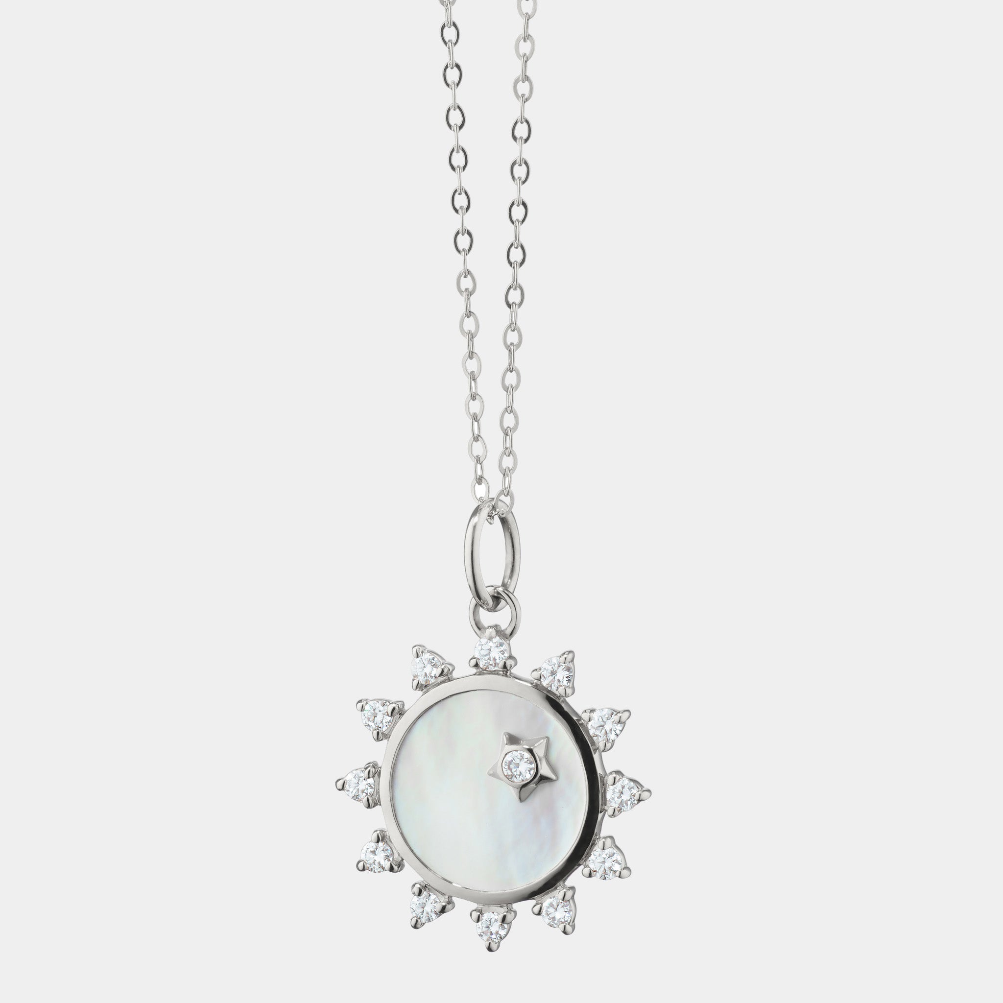Sterling silver white mother of pearl and white sapphire sun pendant on grey background