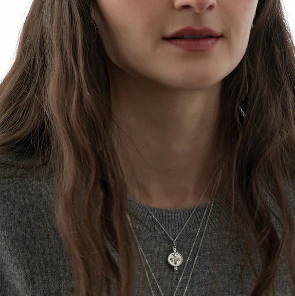 Woman wearing sterling silver pendant necklace with bee and two white sapphires