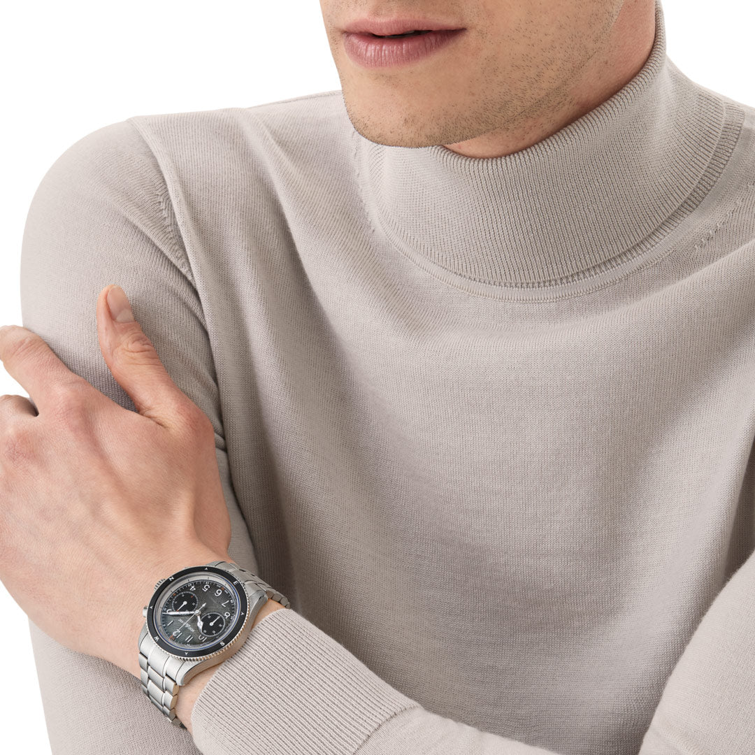 Person wearing a silver watch on a light gray sweater