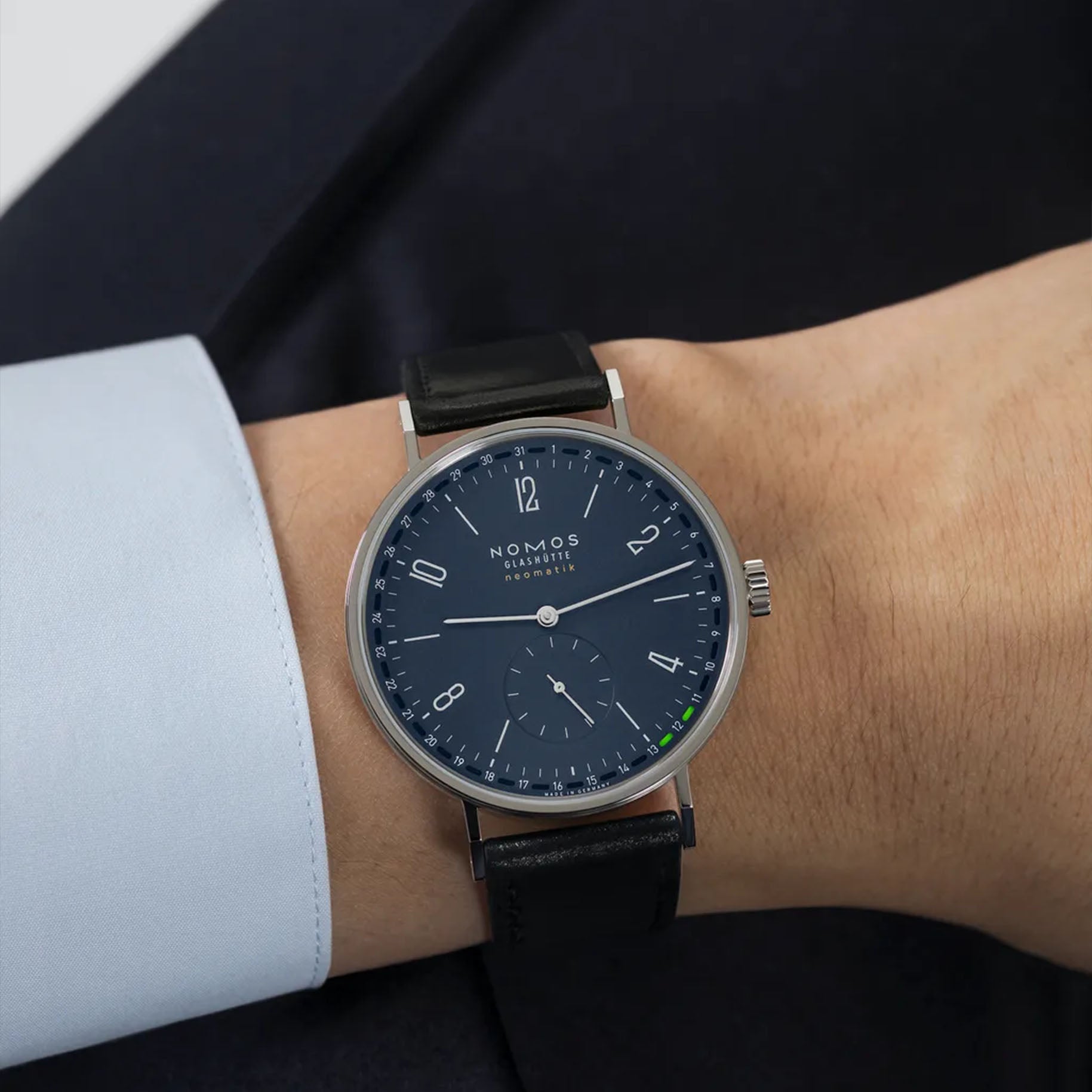 Man wearing NOMOS Glashütte Tangente Neomatik 41mm watch with midnight blue dial, stainless steel case, and black leather strap