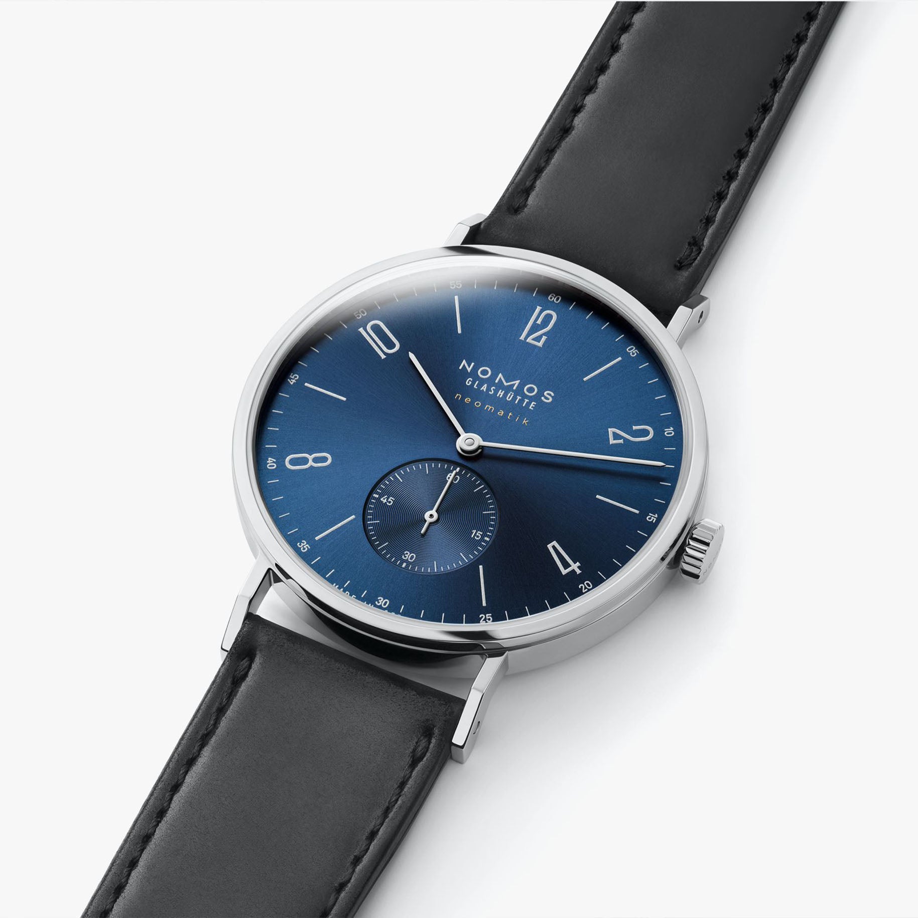 NOMOS Glashütte Tangente Neomatik Blue Gold 39mm automatic watch with blue sunburst dial, stainless steel case, and black leather strap on grey background, flat lay.