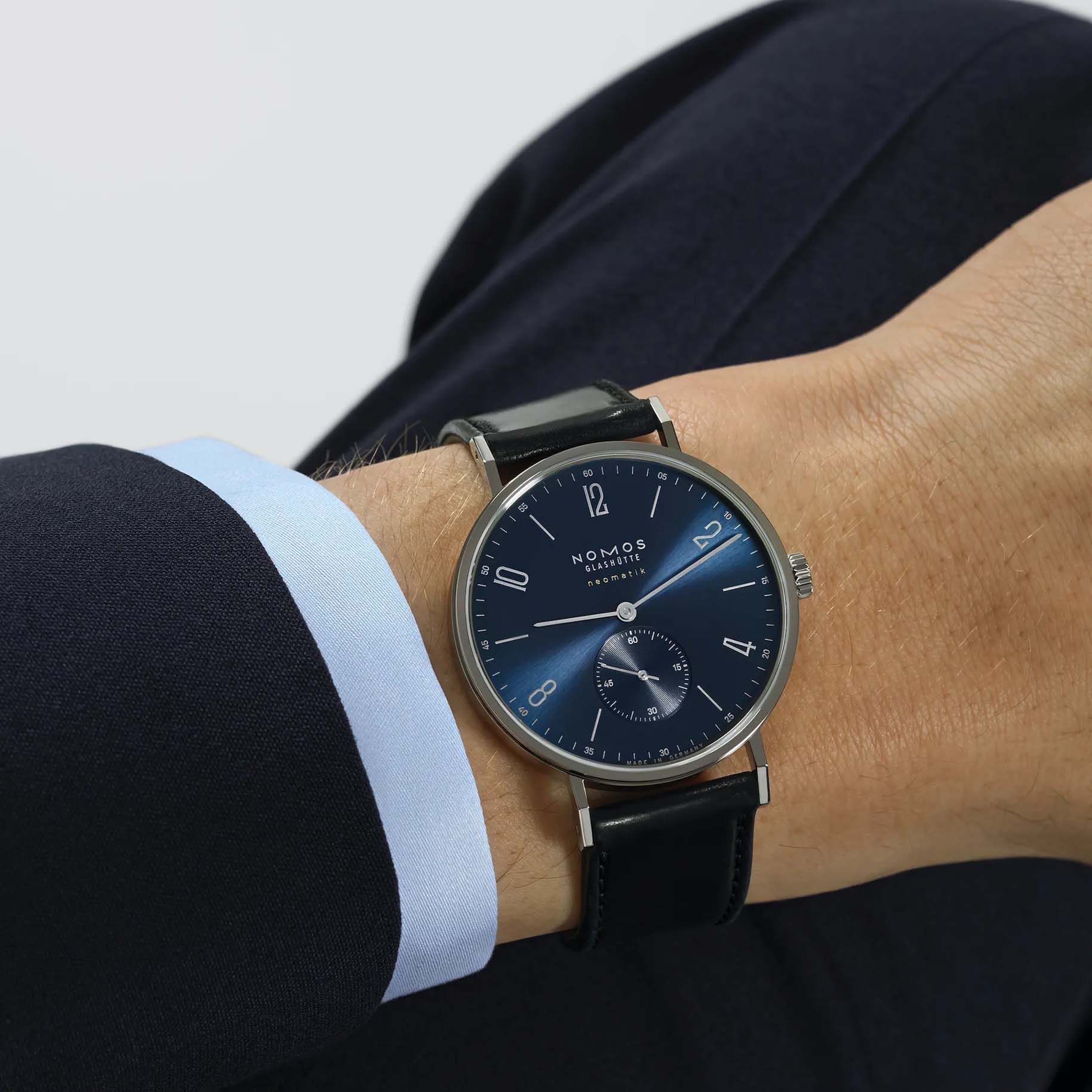 Man wearing NOMOS Glashütte Tangente Neomatik Blue Gold 39mm automatic watch with blue sunburst dial, stainless steel case, and black leather strap.