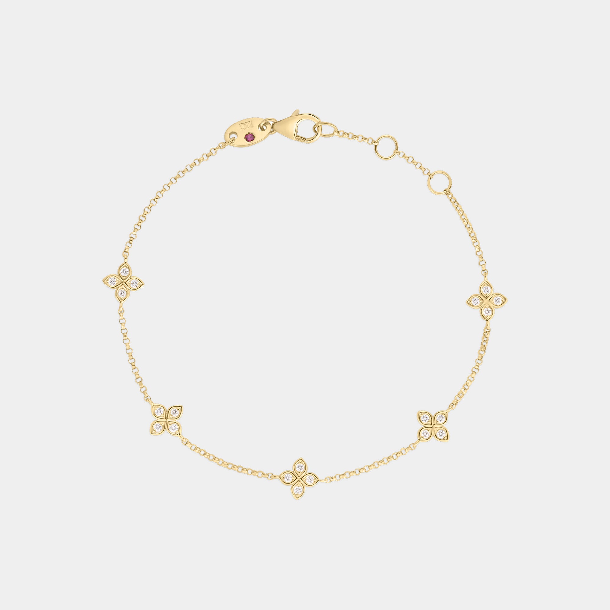 Yellow gold and diamond floral station bracelet on a gray background.