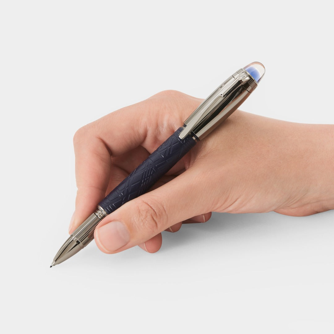 Hand holding a pen with a blue and silver design on a white background