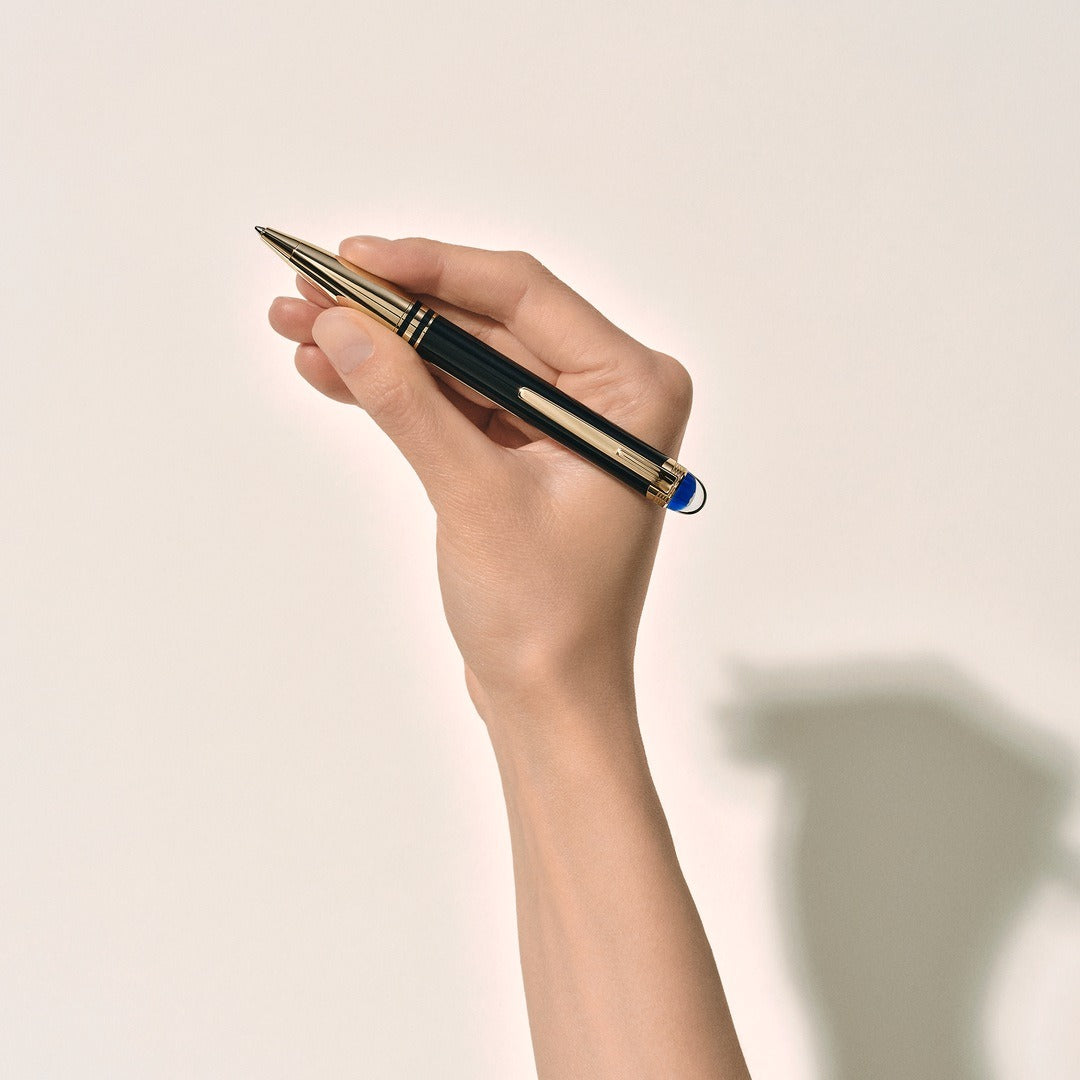 Hand holding a montblanc pen against a plain background