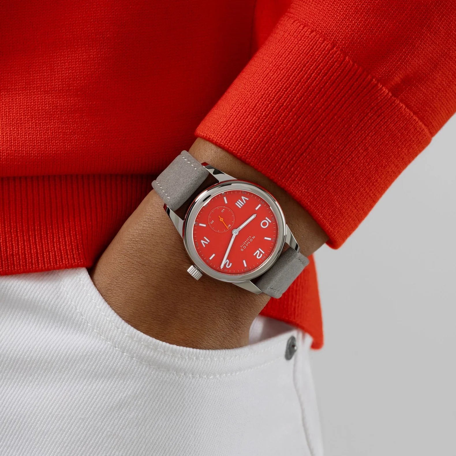 Man wearing NOMOS Glashütte Club Campus 36mm watch with bold red dial, white luminous hands, and vegan velvet gray strap.