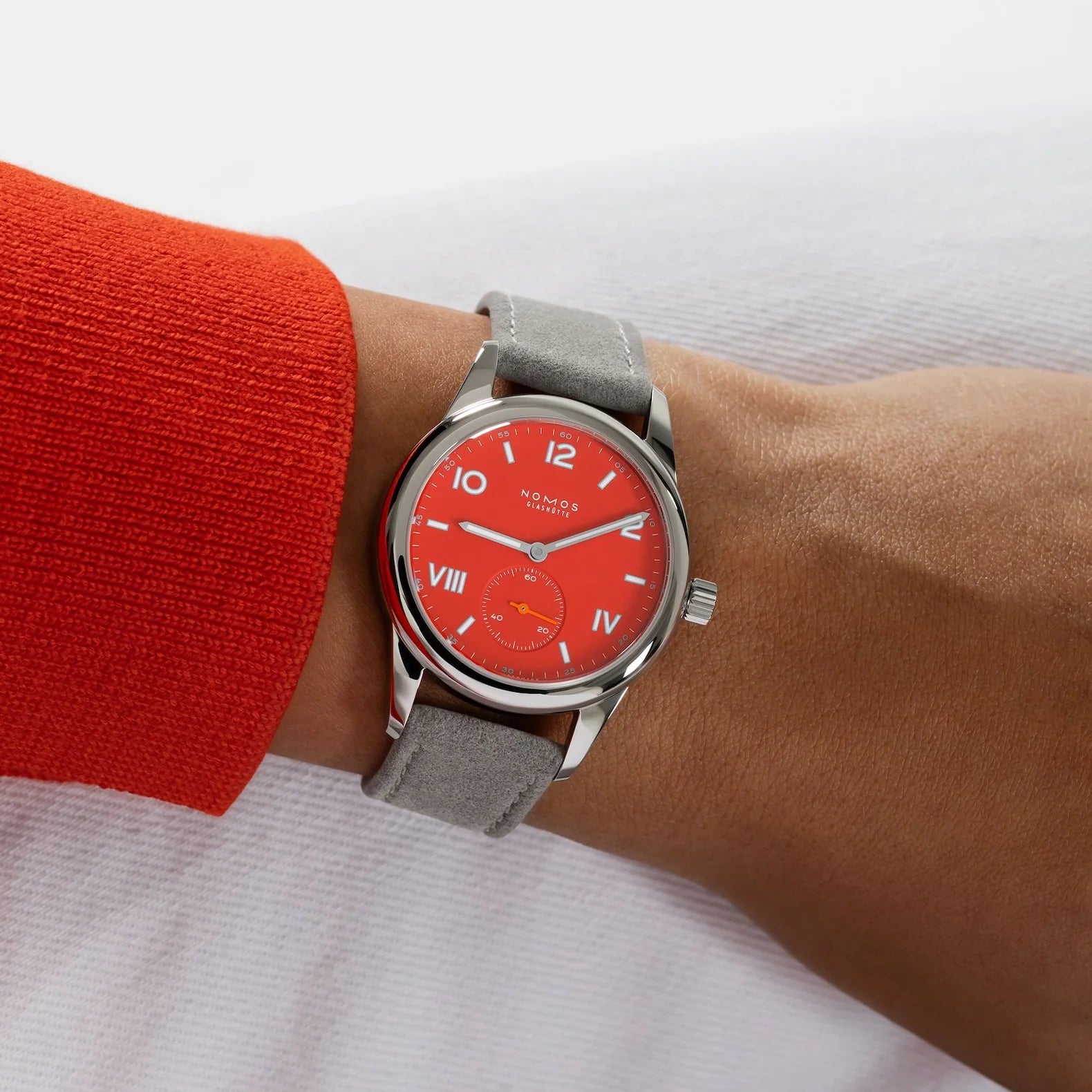 Man wearing NOMOS Glashütte Club Campus 36mm watch with bold red dial, white luminous hands, and vegan velvet gray strap.