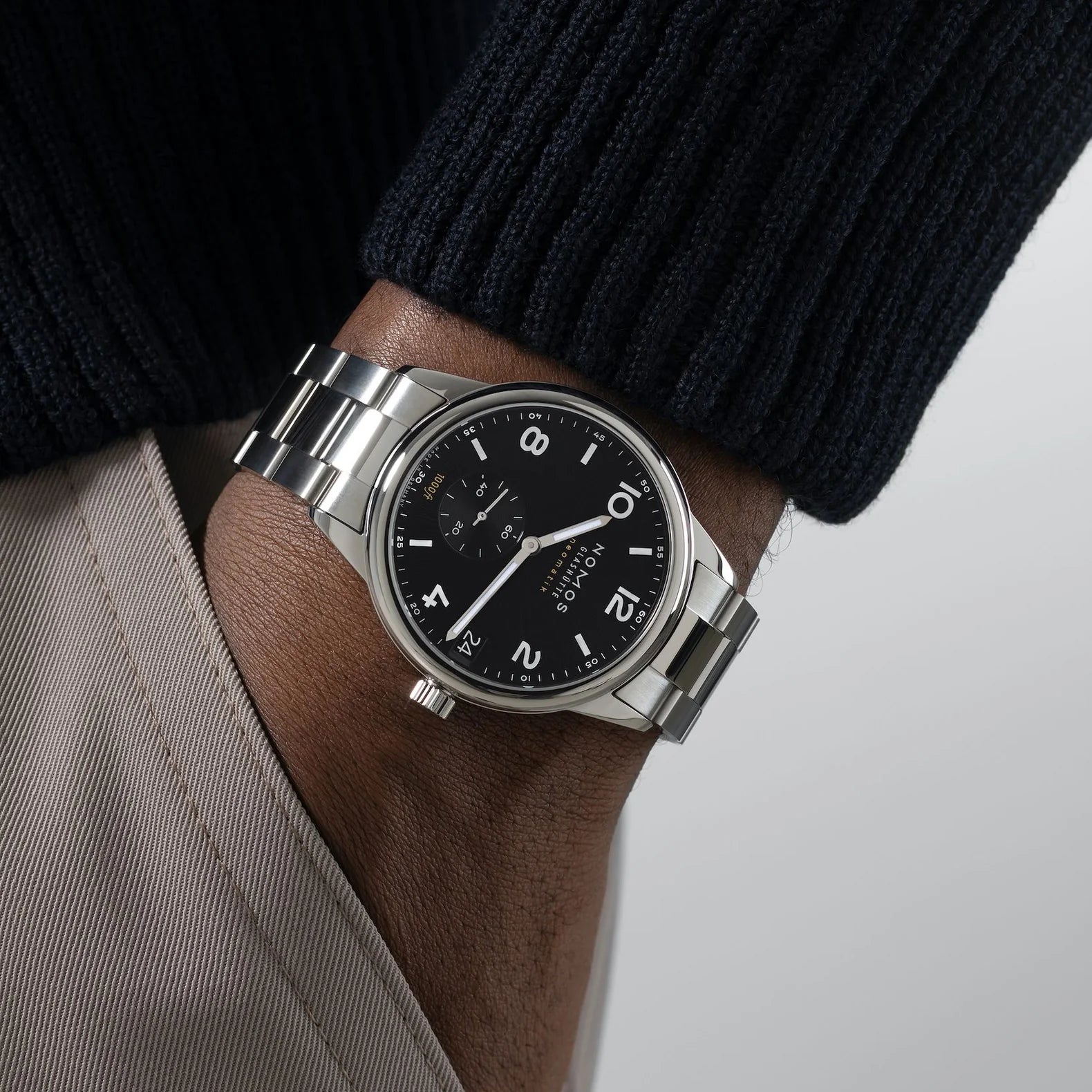 Man wearing NOMOS Glashütte Club Sport Neomatik 42mm watch with black dial, luminous hands, and stainless steel bracelet.