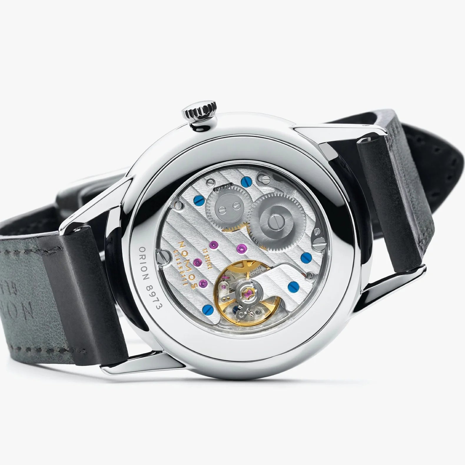 NOMOS Glashütte Orion 38mm watch with white silver-plated dial, tempered blue hands, and black Horween leather strap on white background, laying on side, view of exhibition caseback