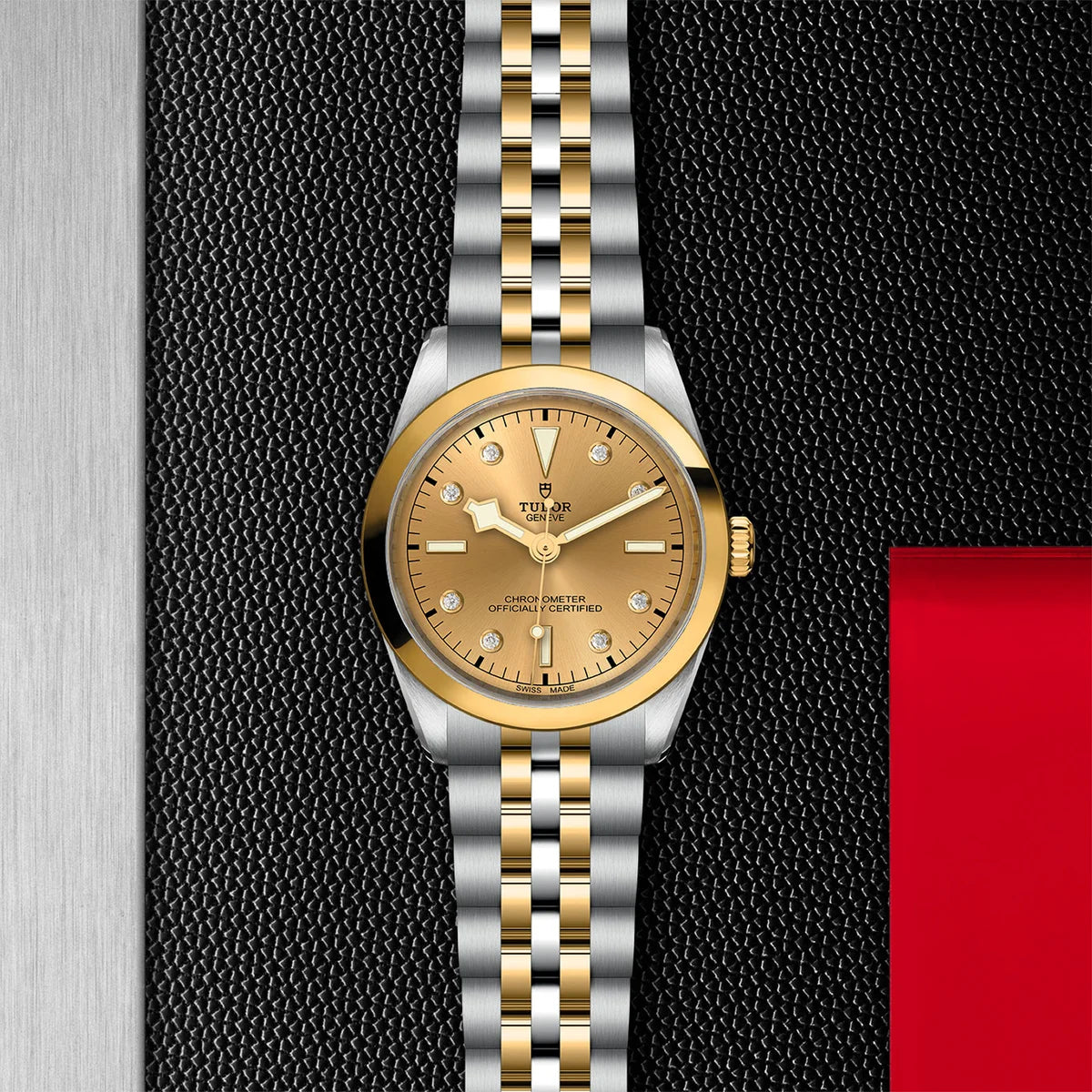 TUDOR black bay one s&g 36mm gold diamond dial watch on 5-link bracelet, displayed in a top-down flat-lay composition on Tudor’s signature textured backdrop.