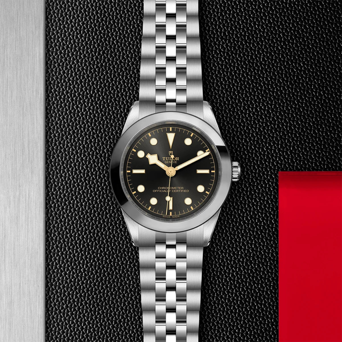 TUDOR black bay one 39mm grey dial watch on 5-link bracelet, displayed in a top-down flat-lay composition on Tudor’s signature textured backdrop.