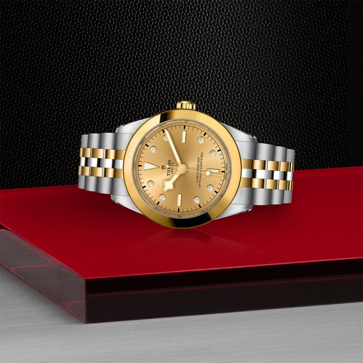 TUDOR black bay one s&g 39mm gold diamond dial watch on 5-link bracelet, shown laying on its side on Tudor’s signature red platform.