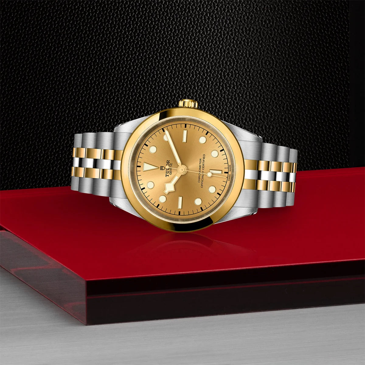 TUDOR black bay one s&g 41mm gold dial watch on 5-link bracelet, shown laying on its side on Tudor’s signature red platform.