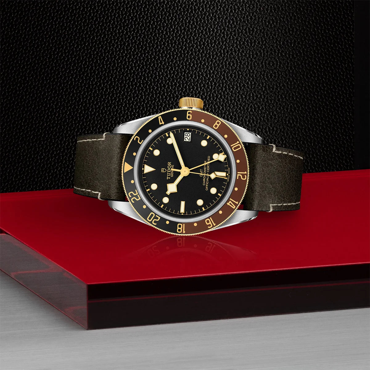 TUDOR black bay gmt s&g 41mm black dial watch on leather strap, shown laying on its side on Tudor’s signature red platform.
