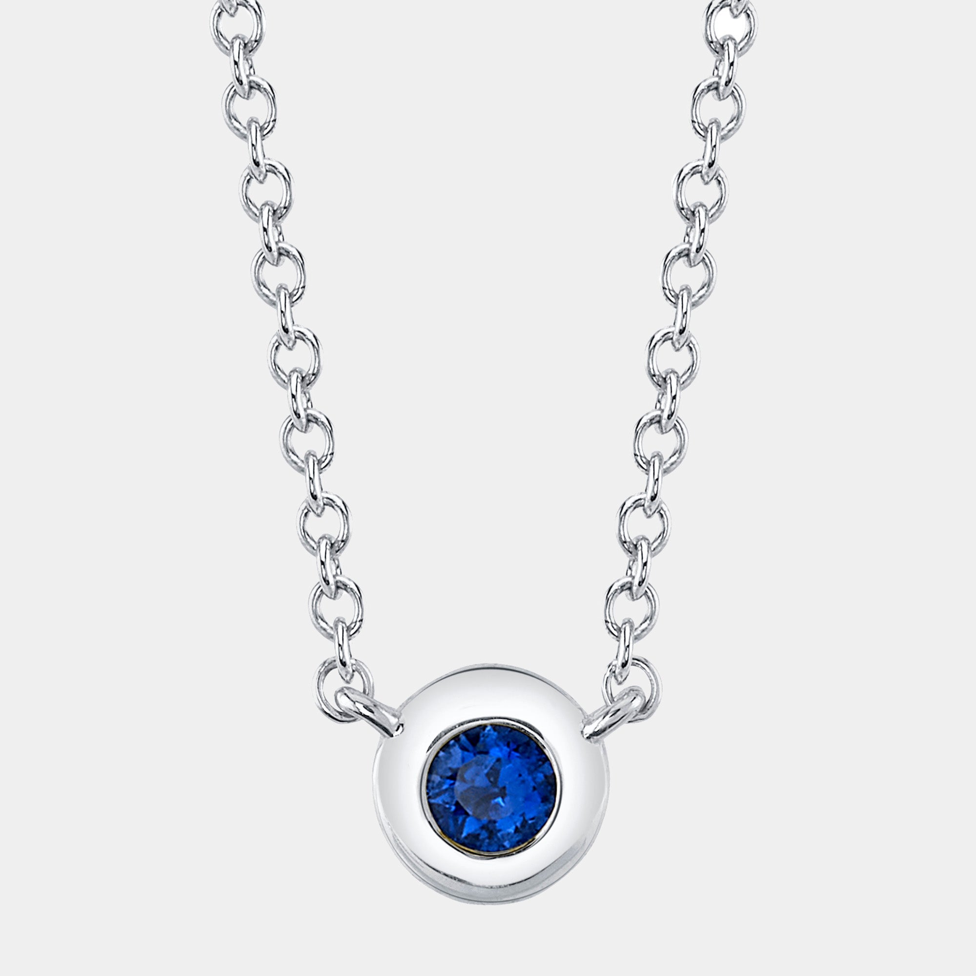 White Gold necklace with a blue sapphire on a white background