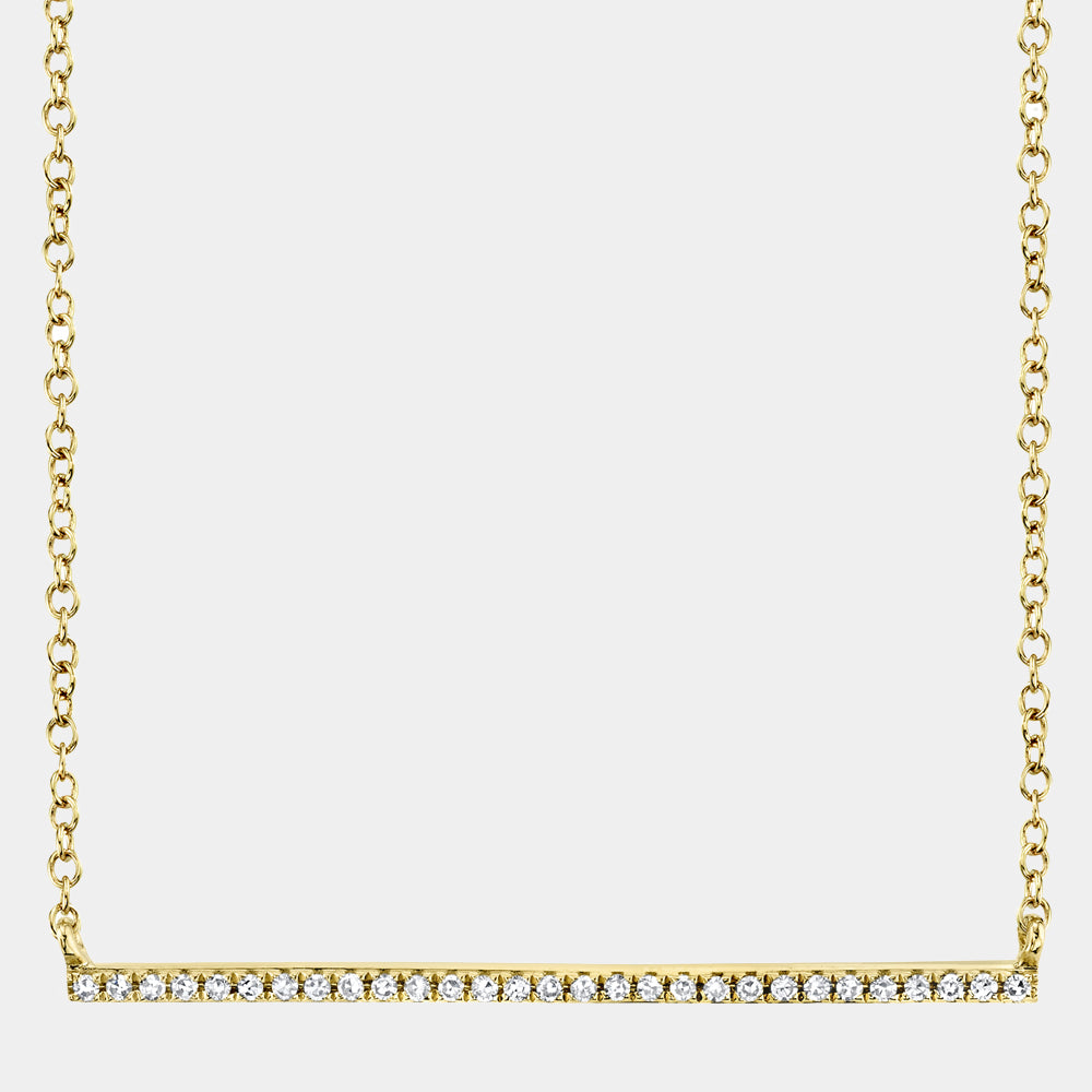 Gold necklace with a bar pendant on a light gray background