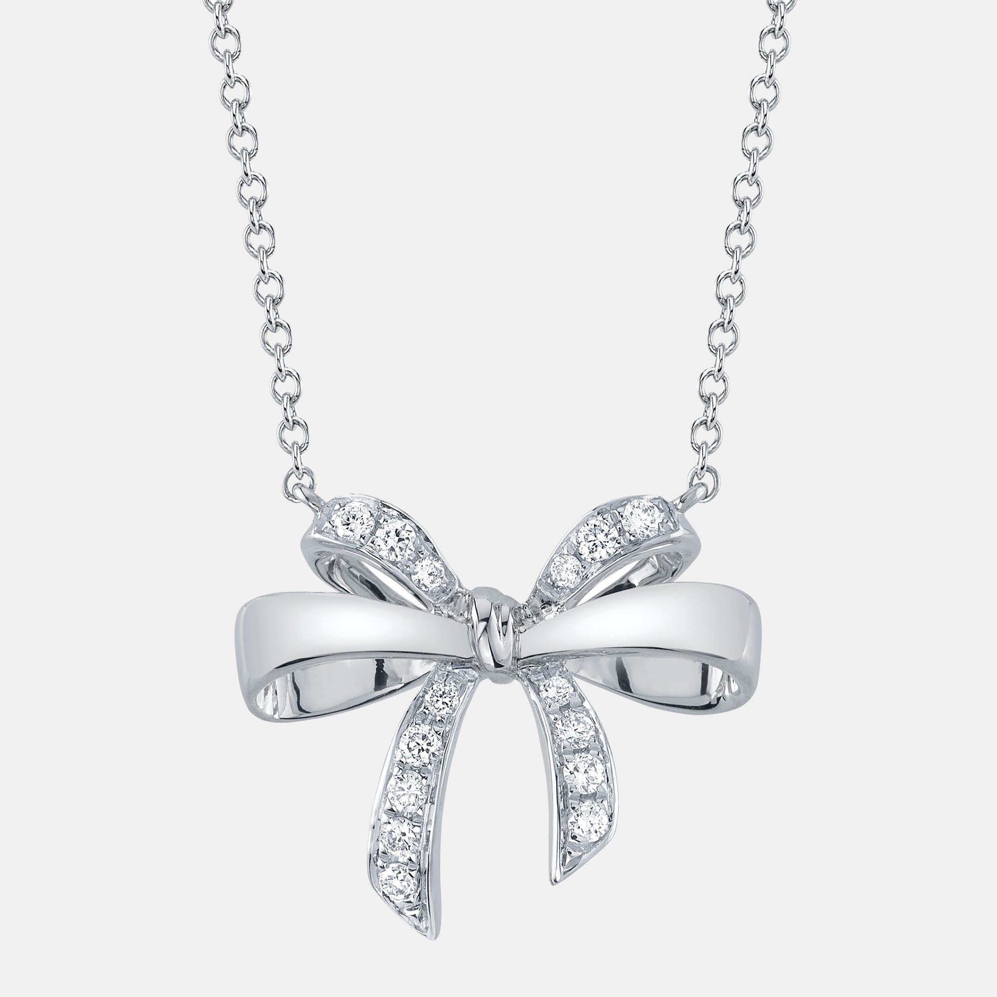 Silver bow-shaped pendant necklace with diamonds on a light gray background