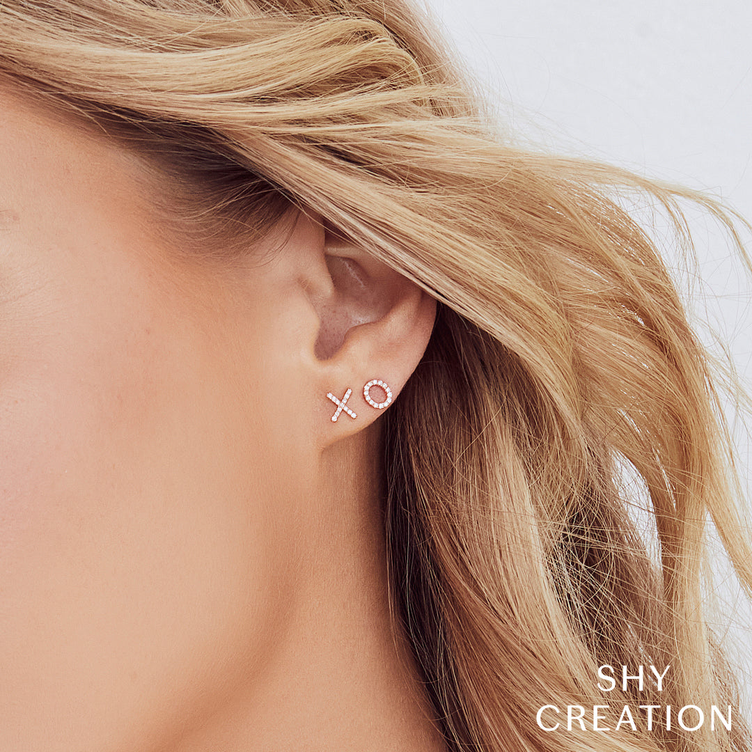 Woman wearing rose gold diamond "xo" stud earrings