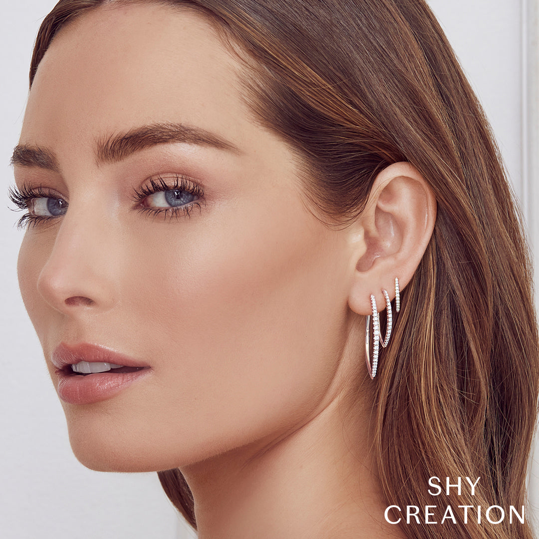 Woman wearing various white gold diamond hoop earrings