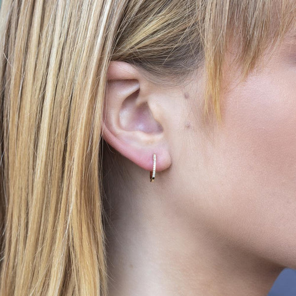 Woman wearing yellow gold diamond huggie earrings