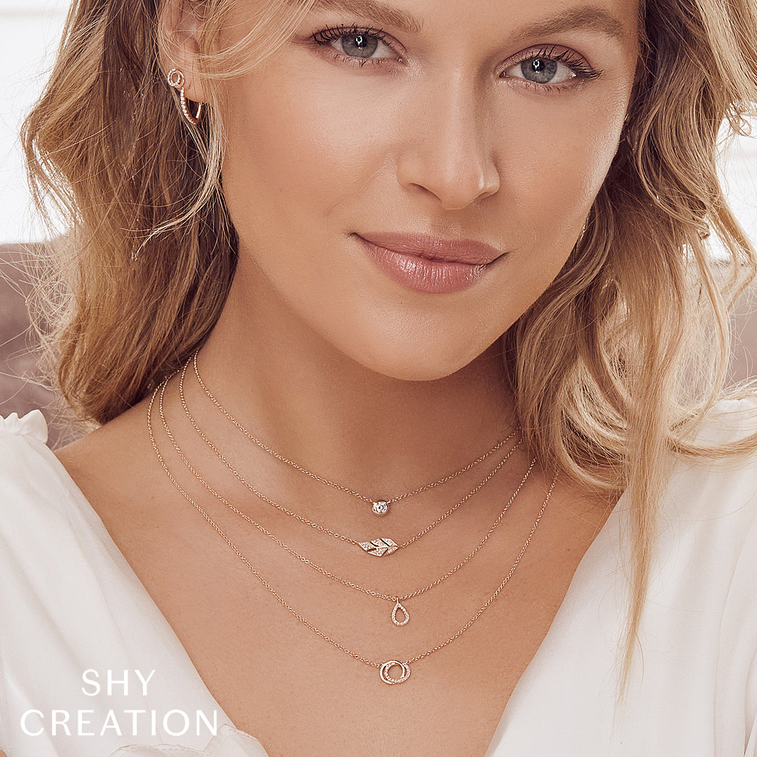 Woman wearing multiple necklaces with 'SHY CREATION' branding.