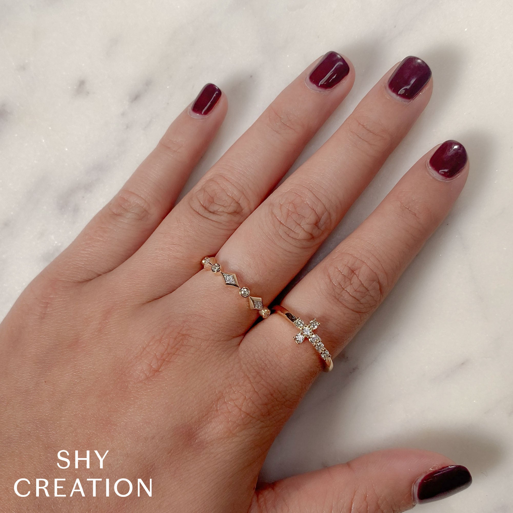 Woman's hand wearing yellow gold east-west diamond cross ring