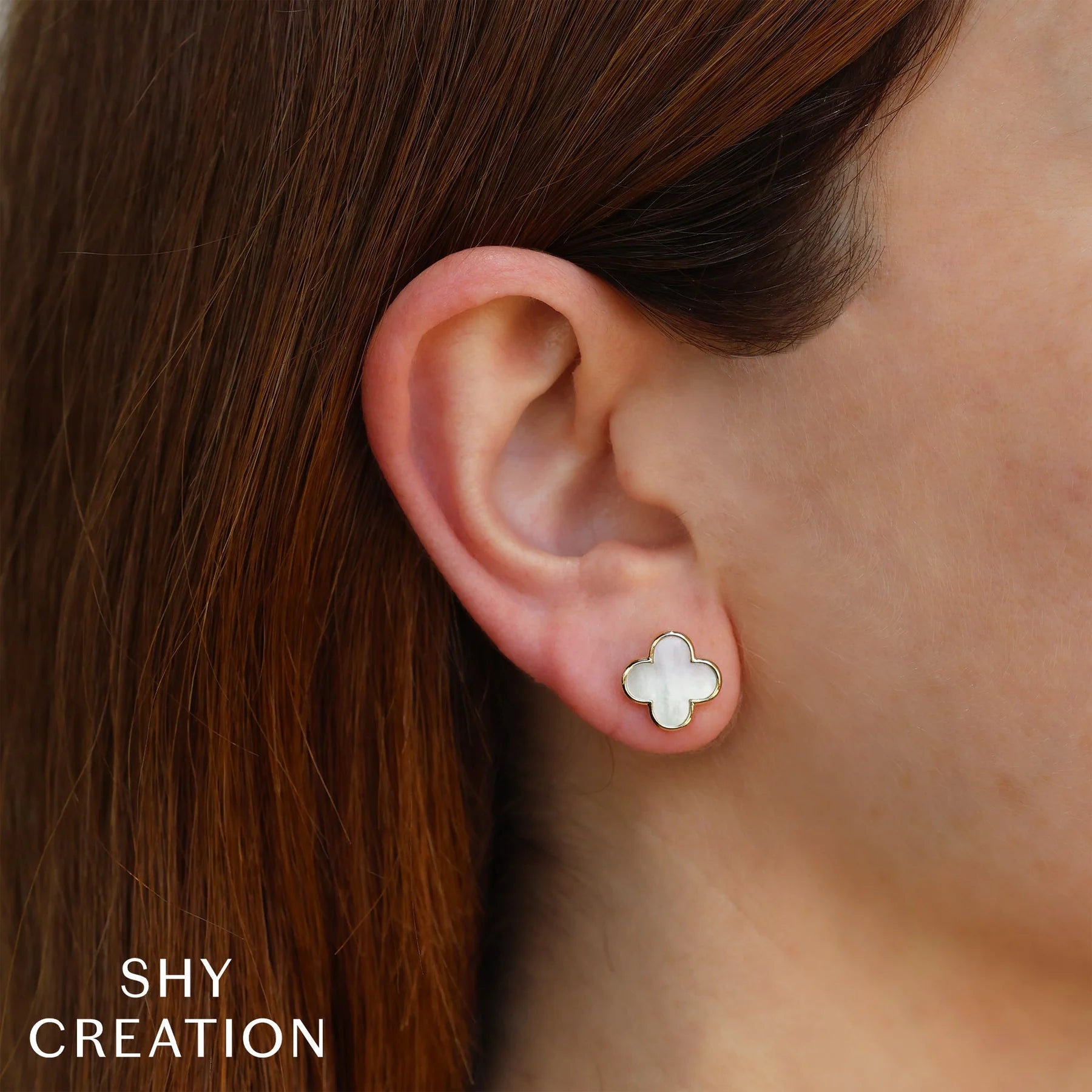 Woman wearing yellow gold mother of pearl clover stud earrings