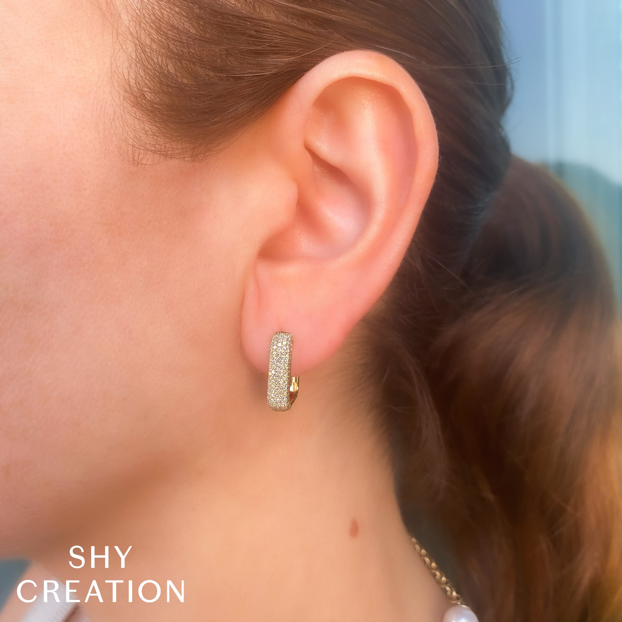 Woman wearing yellow gold pave diamond rectangular hoop earrings front angle view