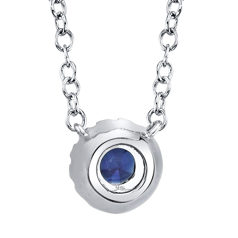 Back view of white gold necklace with a blue sapphire pendant on a white background
