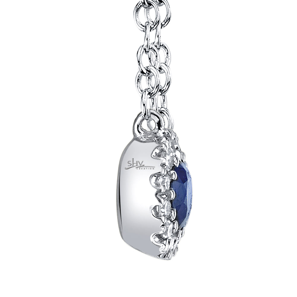 Side view of white gold necklace with a blue sapphire pendant on a white background