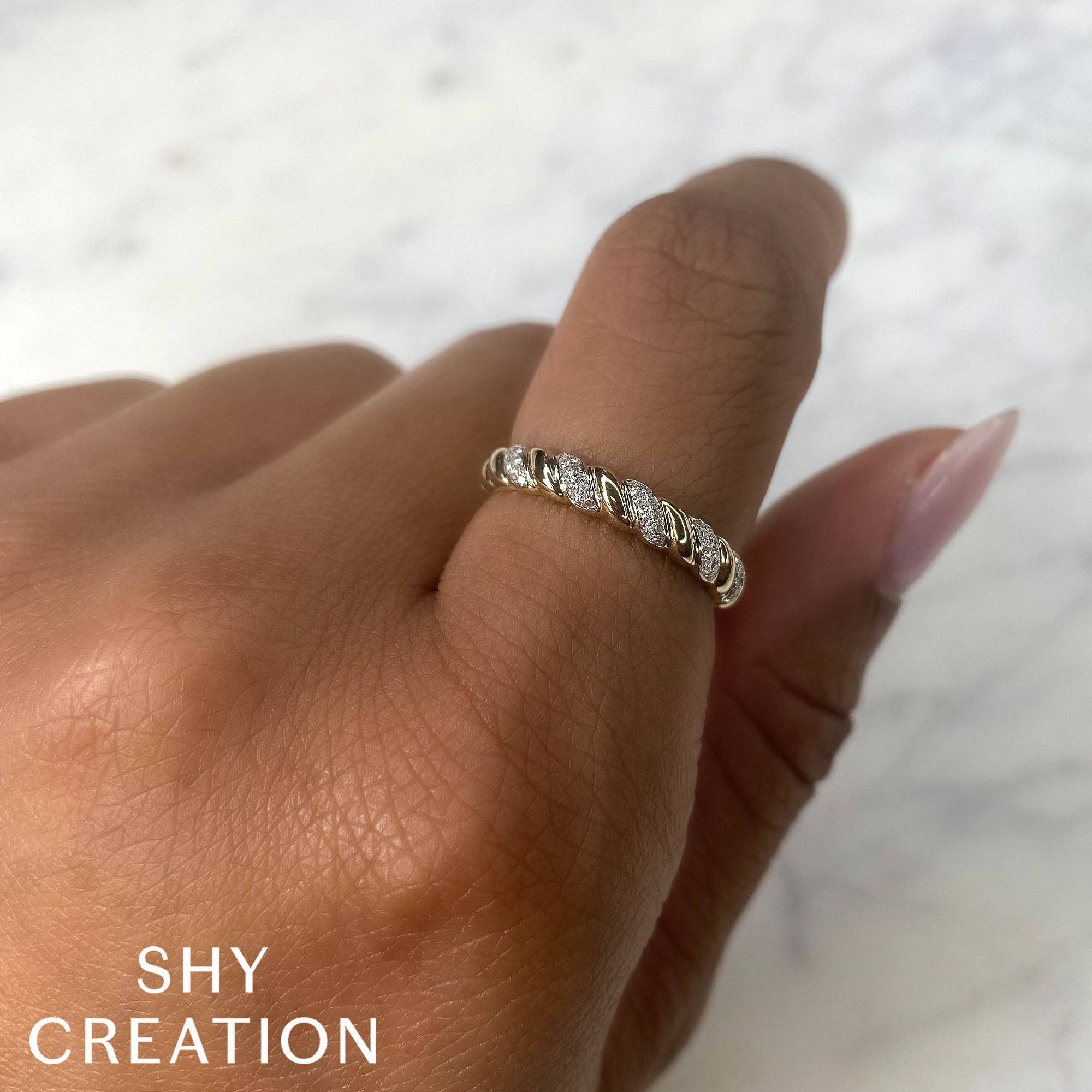 Woman's hand wearing yellow gold twist diamond fashion ring