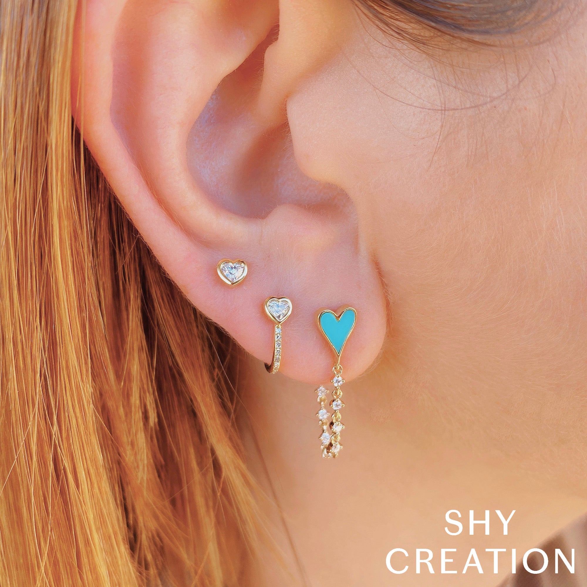 Closeup of woman wearing yellow gold bezel set heart shaped diamond stud earrings