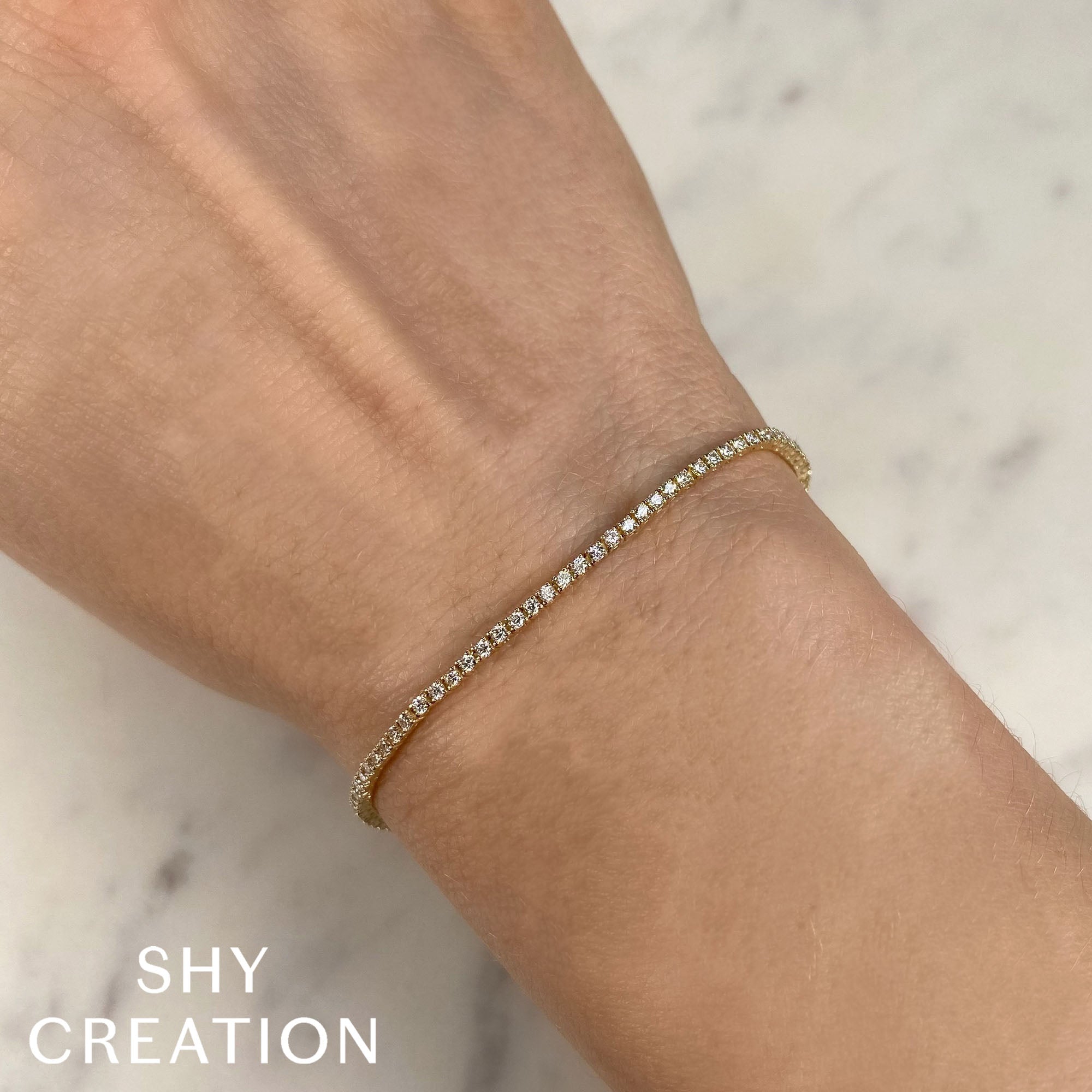 Woman wearing yellow gold diamond tennis bracelet, closeup wrist view