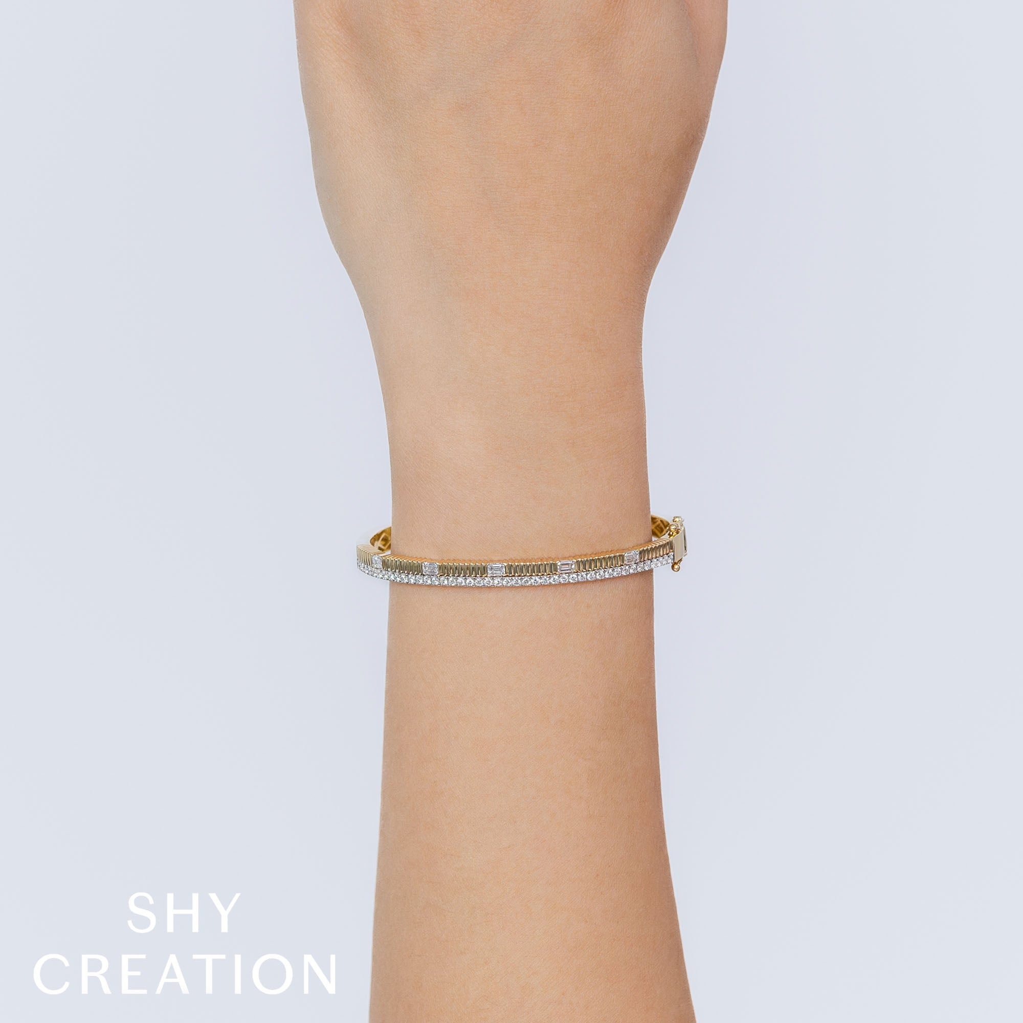 Woman's wrist wearing yellow gold diamond ribbed bangle bracelet