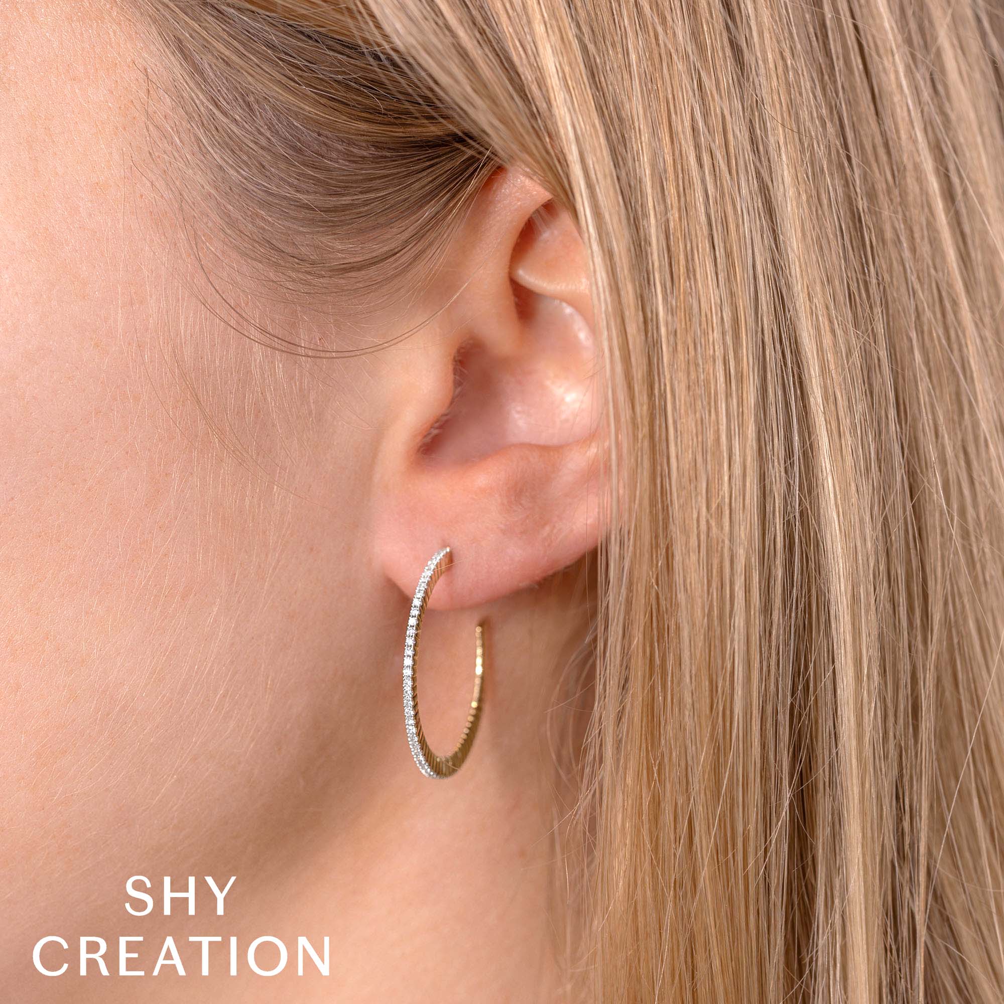 Woman wearing, yellow gold diamond hoop earrings