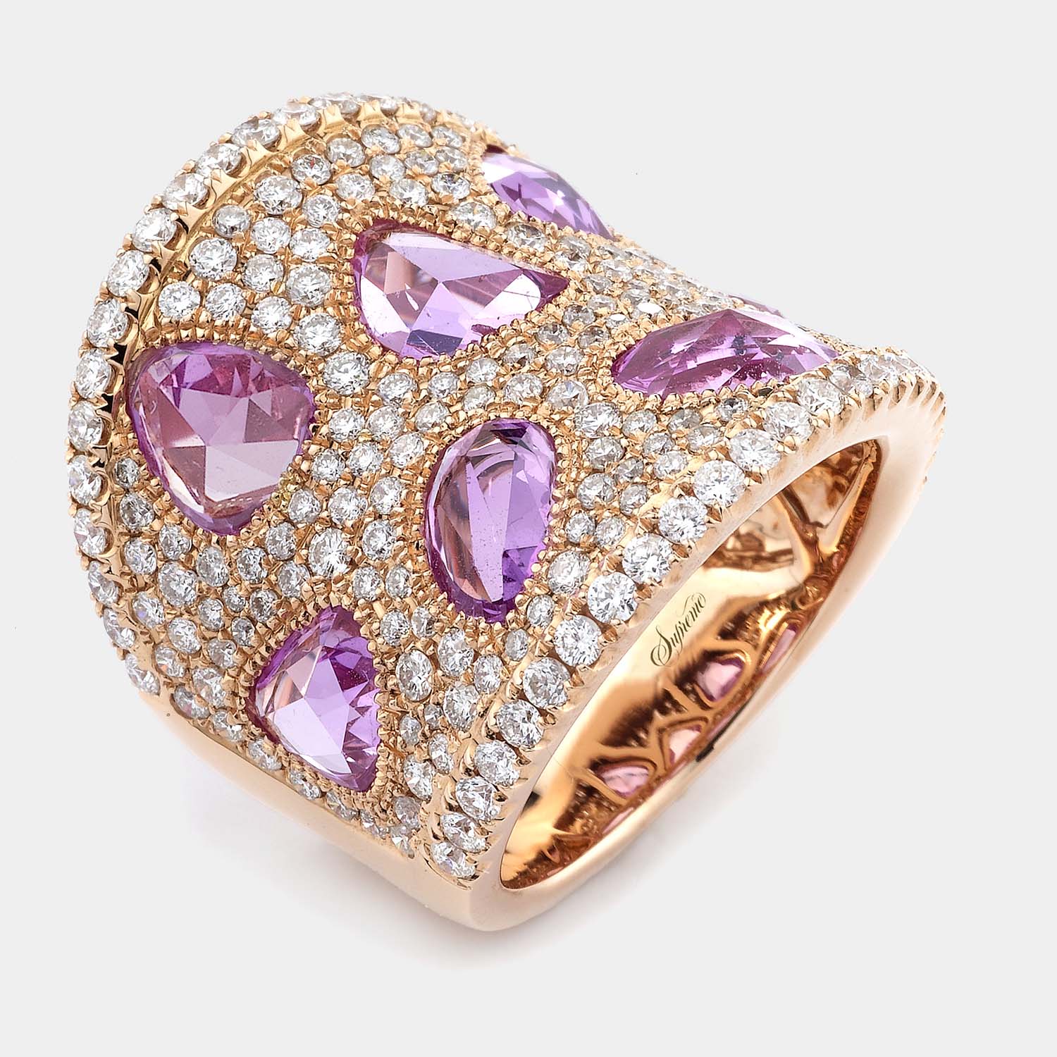 18K rose gold wide band ring with pear and mixed-shape sapphires surrounded by pavé-set round diamonds, shown on a grey background in a front angle view.