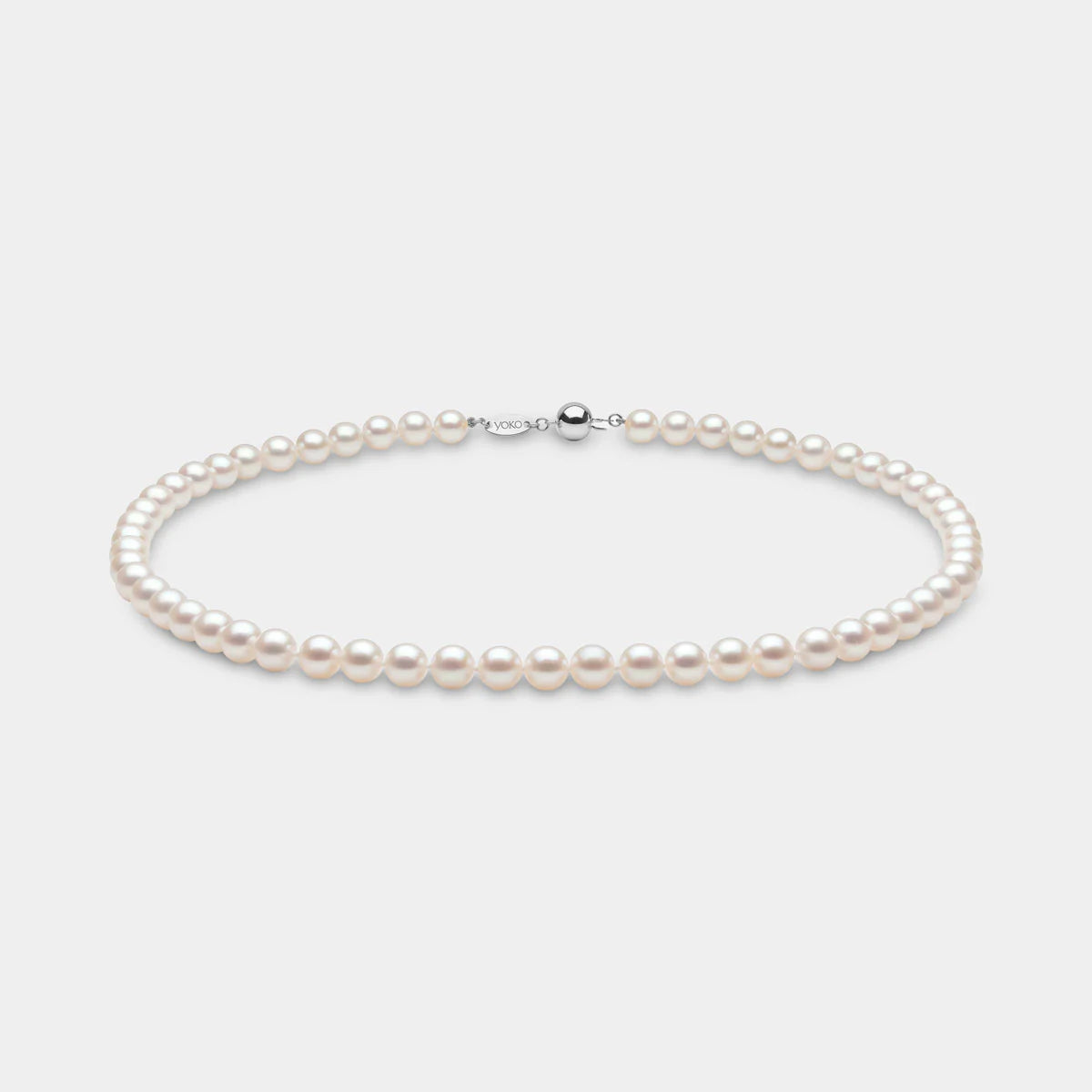Classic akoya pearl strand necklace on grey background with white gold clasp