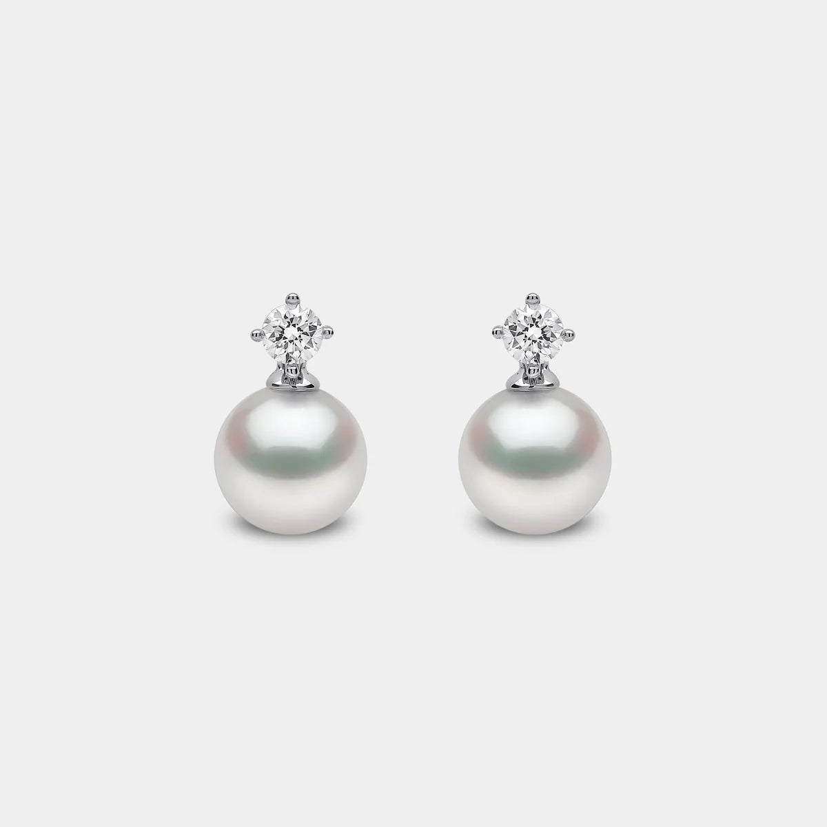 White gold pearl and diamond drop earrings on grey background, front view