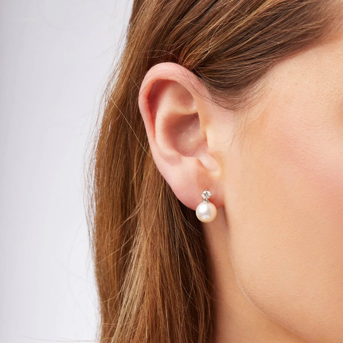 Pearl earring worn by a person with a plain background