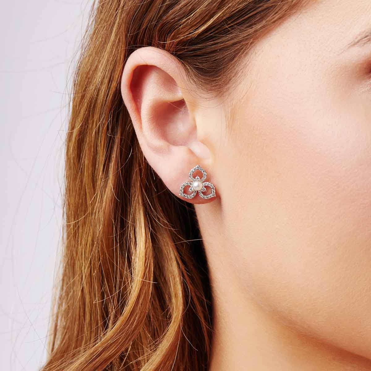 Close-up of a woman's ear wearing a white gold earring with a pearl center.