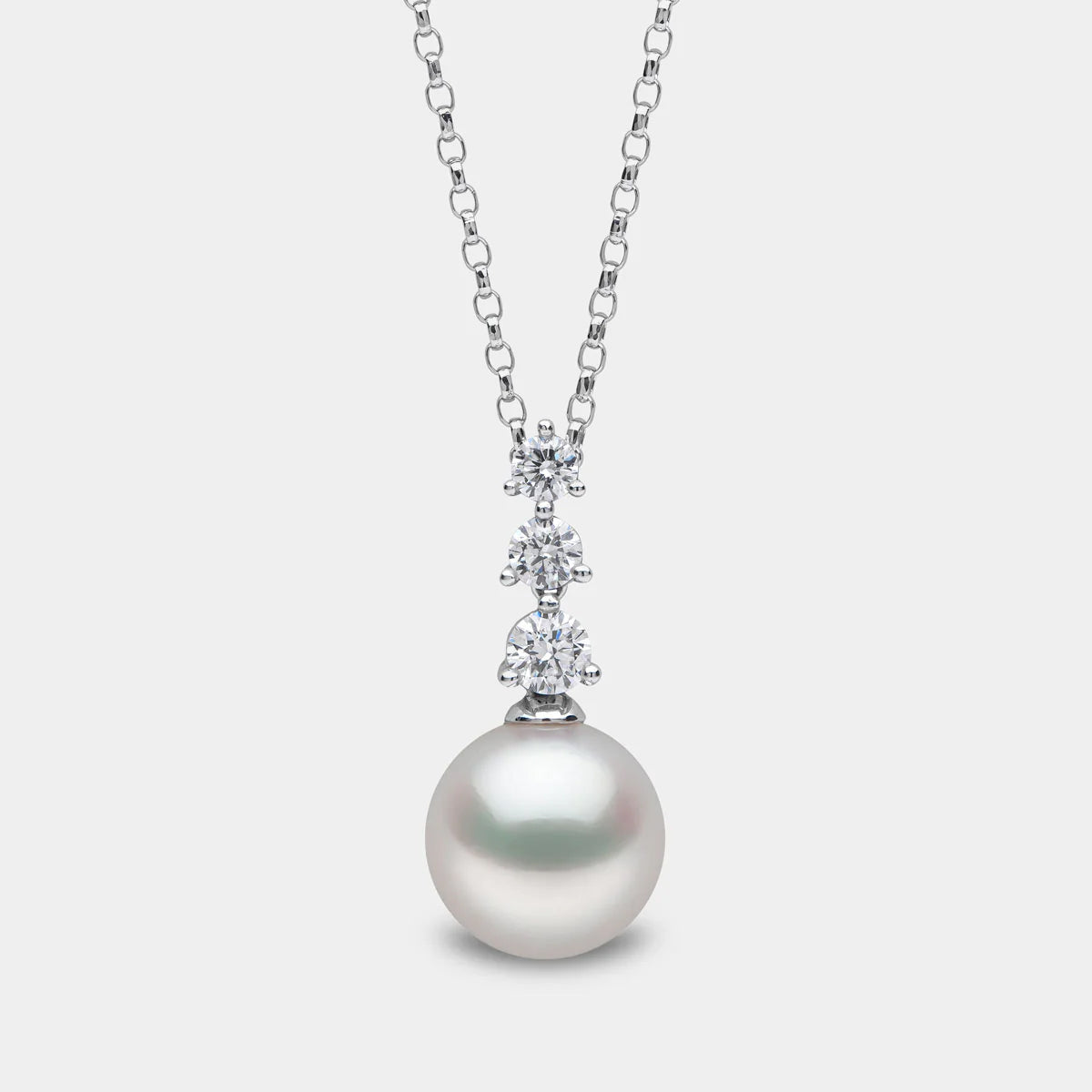 White gold pearl pendant necklace with three diamond accents on grey background, front view
