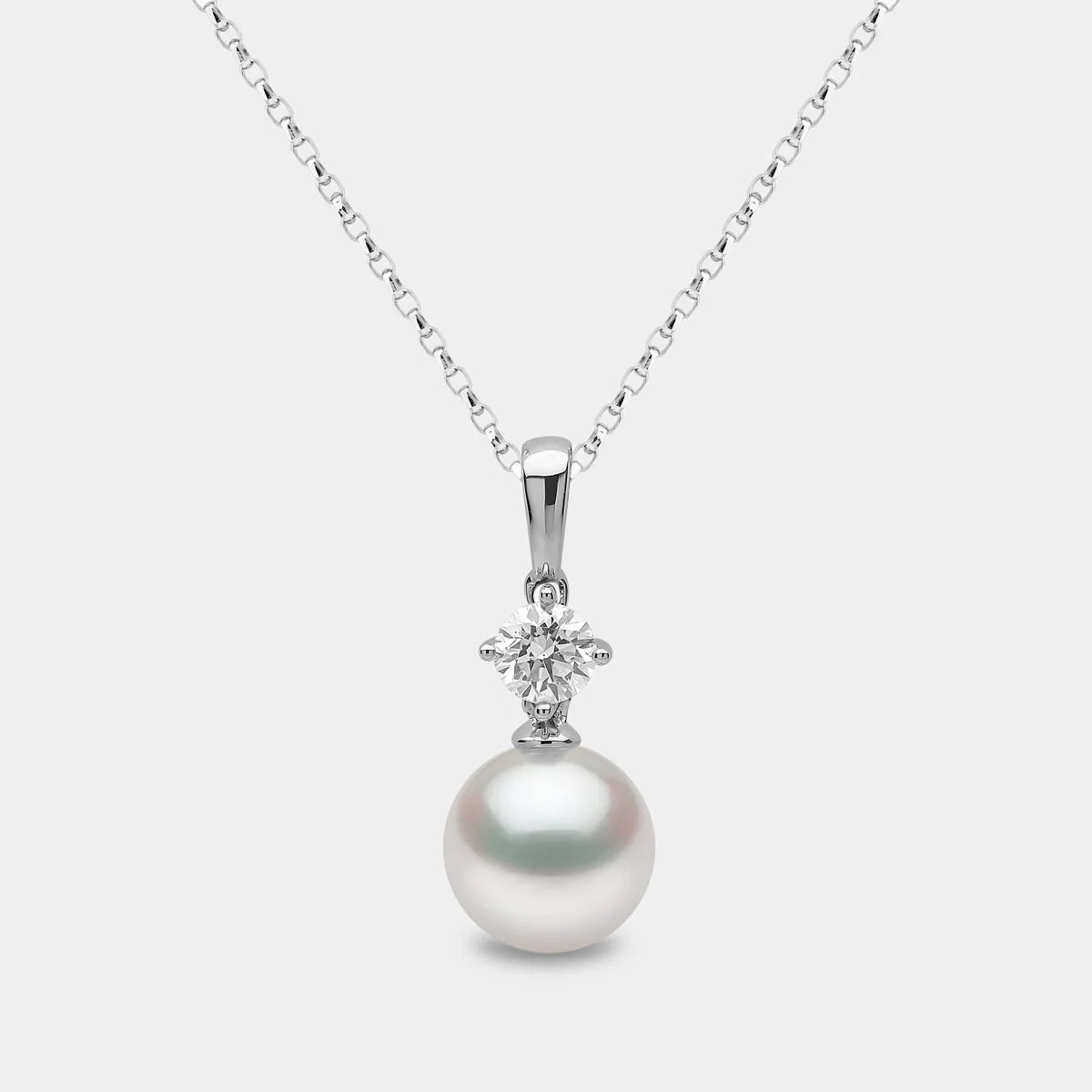 White gold pearl pedant necklace with solitaire diamond accent on grey background, front view