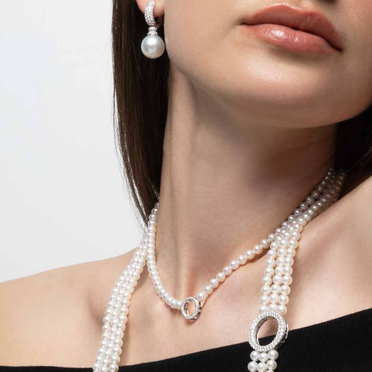 Pearl necklace and earrings on a model against a neutral background